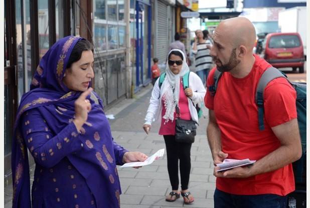 An Acorn member conversing with a woman while handing out flyers on the street.